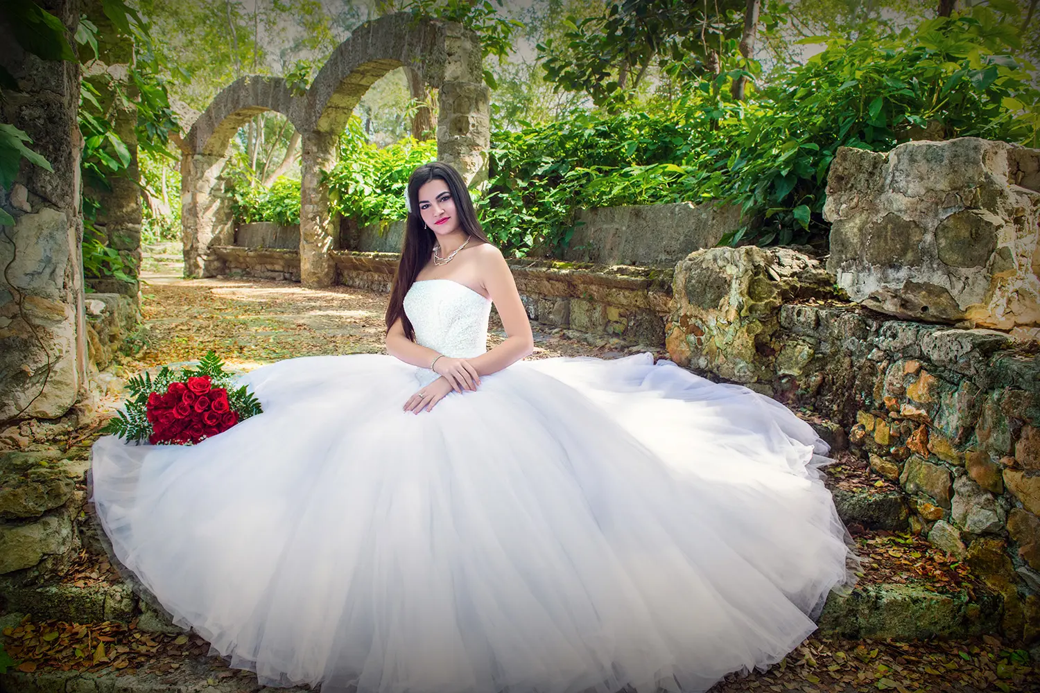 Bonita jovencita con vestido blanco desplegado sobre escaleras de piedra en el bosque