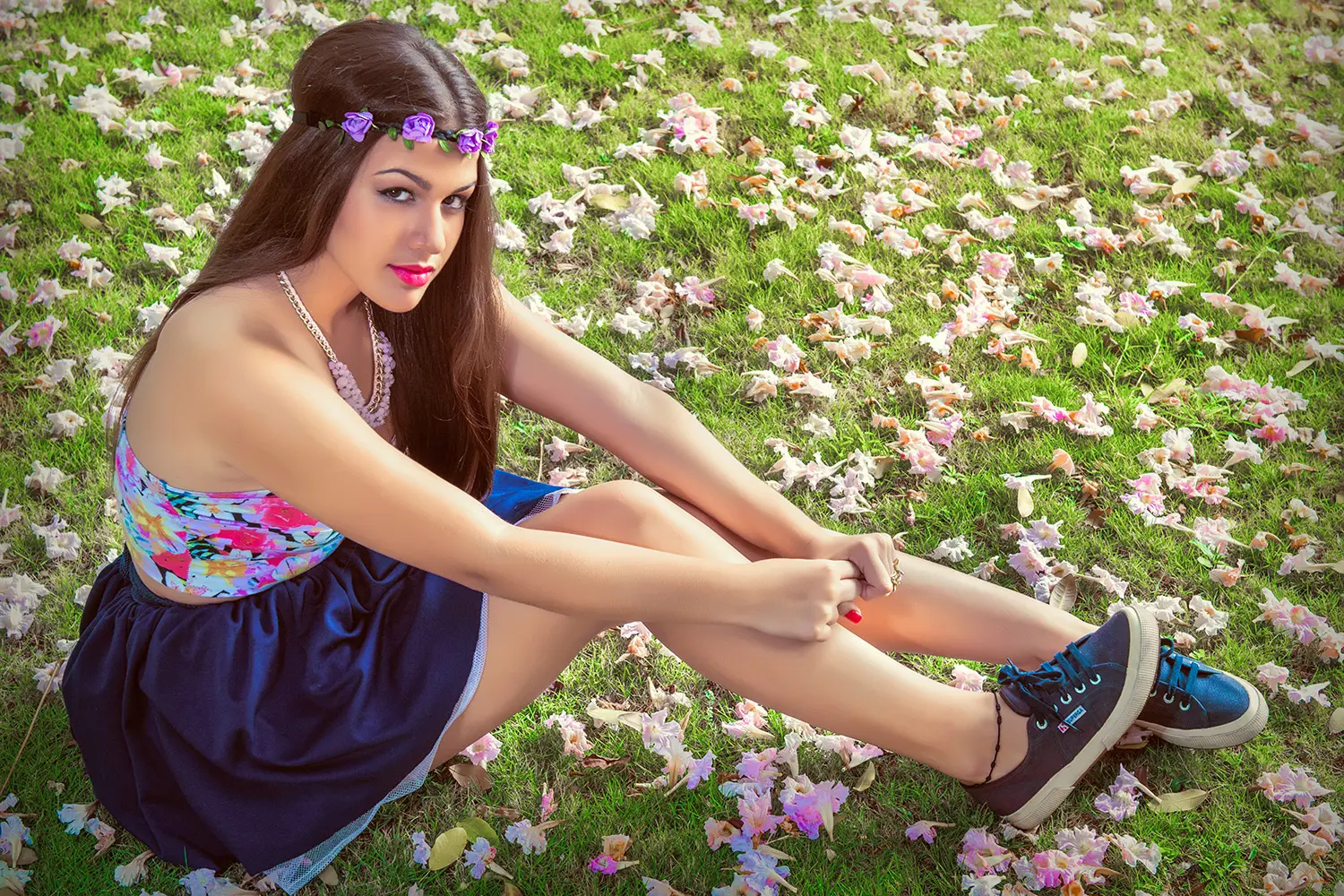 Muchacha sentada sobre césped verde y flores rosas