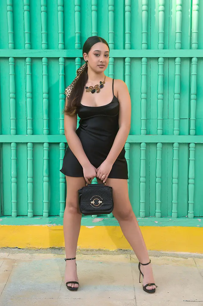 Jovencita posando delante de puertas coloniales verdes