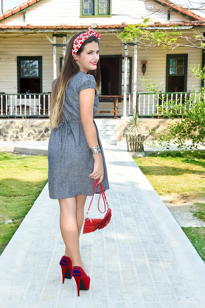 modelo con pañuelo rojo caminando hacia casa de madera