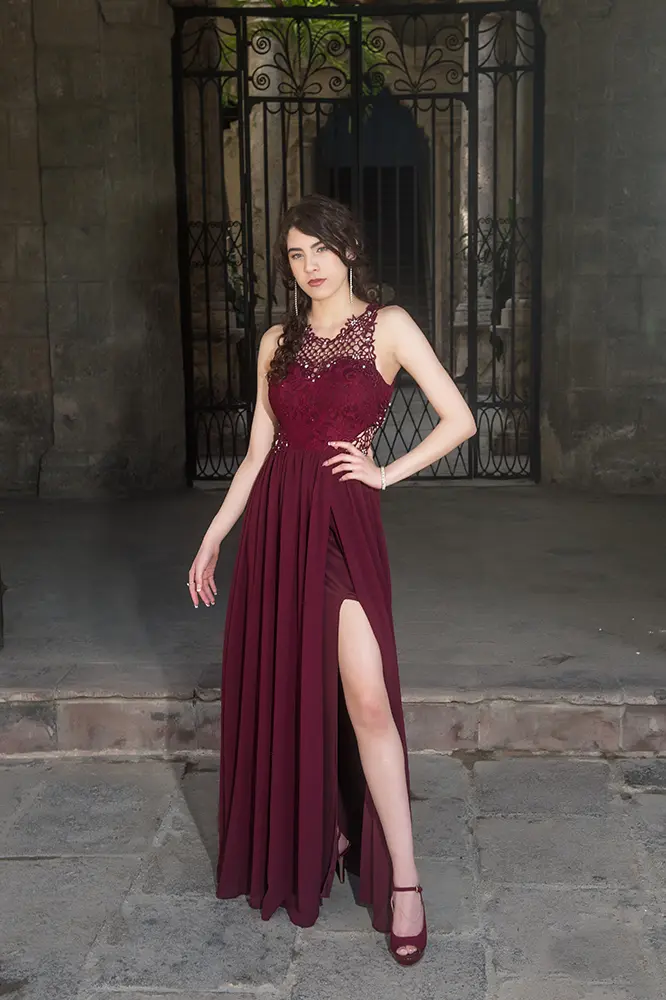 Chica alta con vestido rojo vino posando frente a edificio estilo colonial