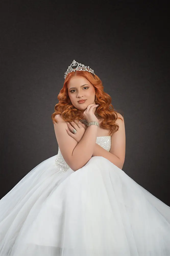 Modelo en plano medio sentada con vestido clásico blanco