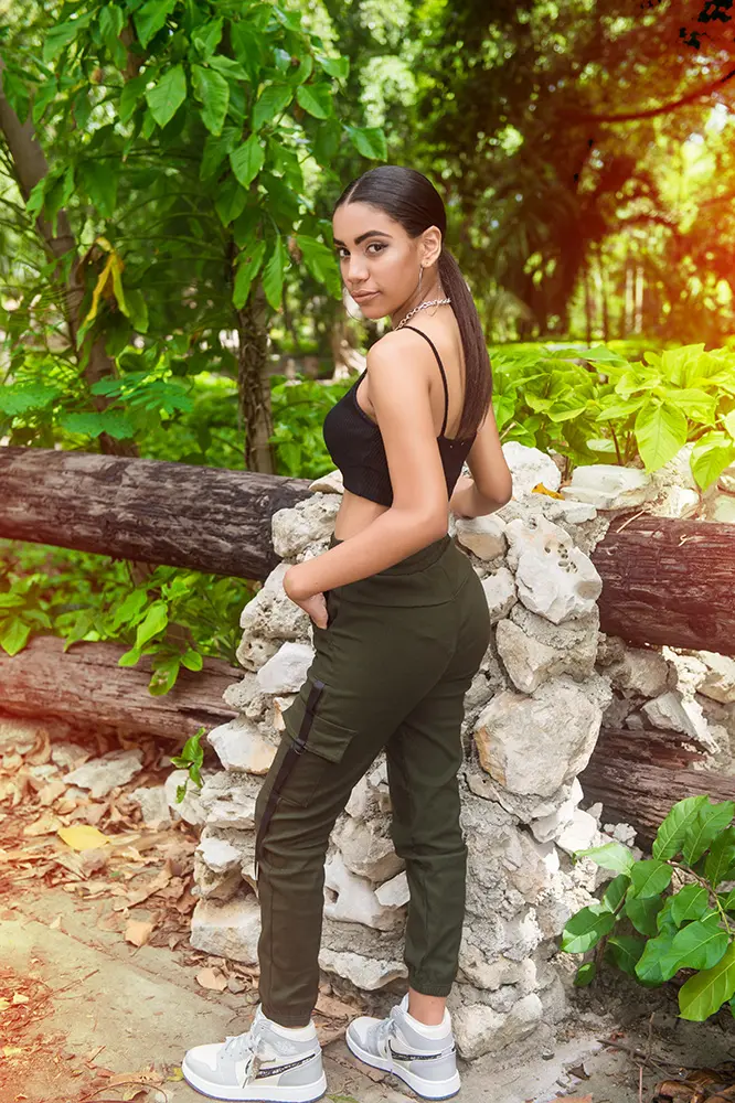 Muchacha morena posando de lado en ambiente campestre