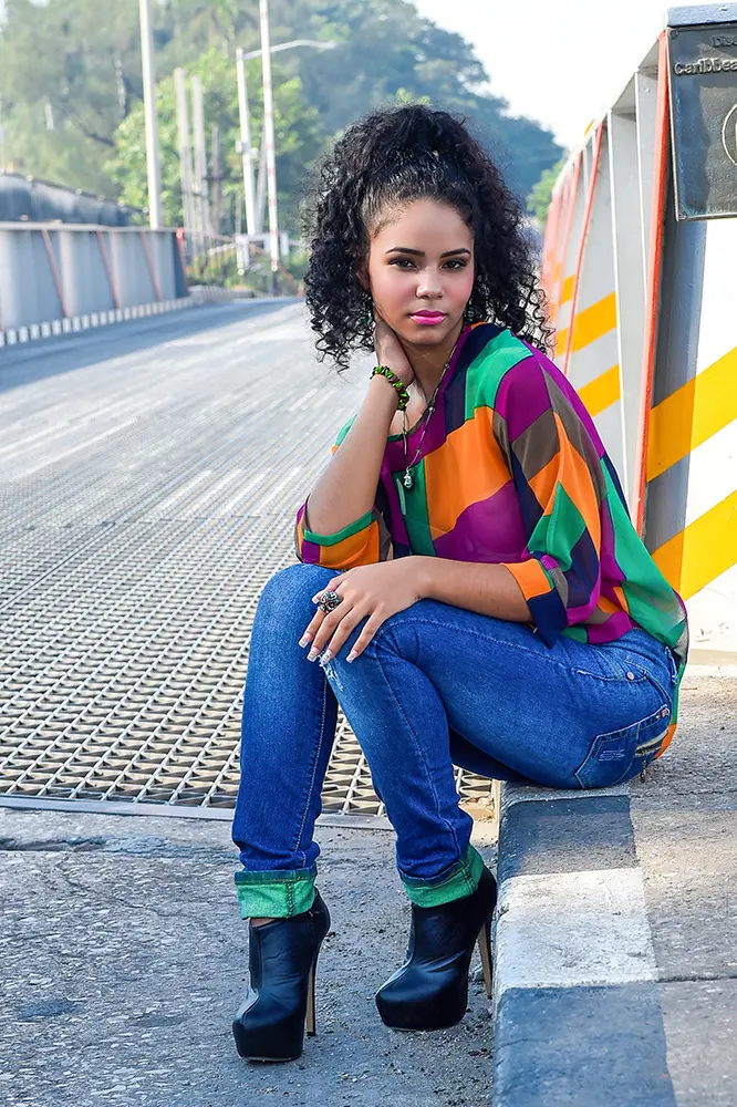 Joven sentada en borde de la acera frente a un puente